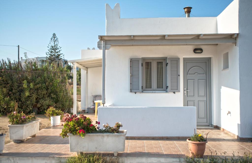 a white house with potted plants in front of it at Molos Studios in Naxos Chora