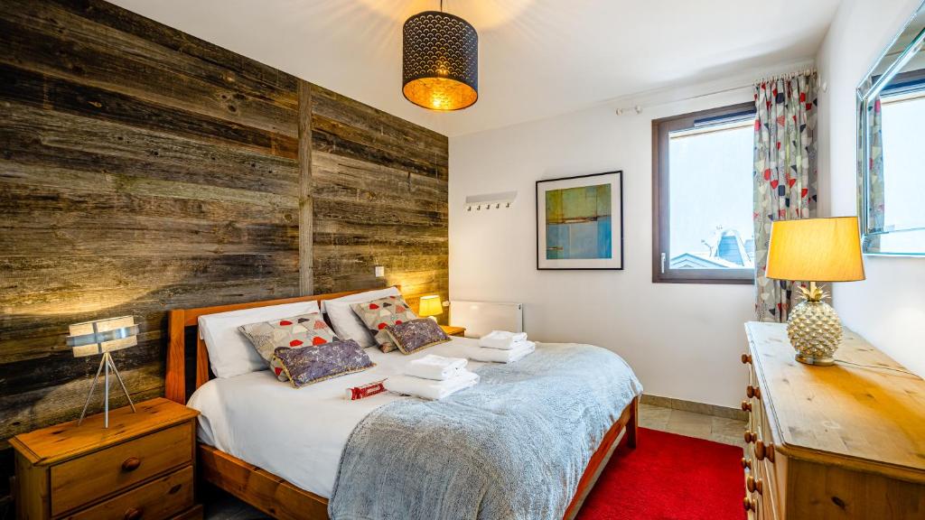 une chambre avec un lit et un mur en bois dans l'établissement Les Freinets - Apt D102 - BO Immobilier - Châtel, à Châtel