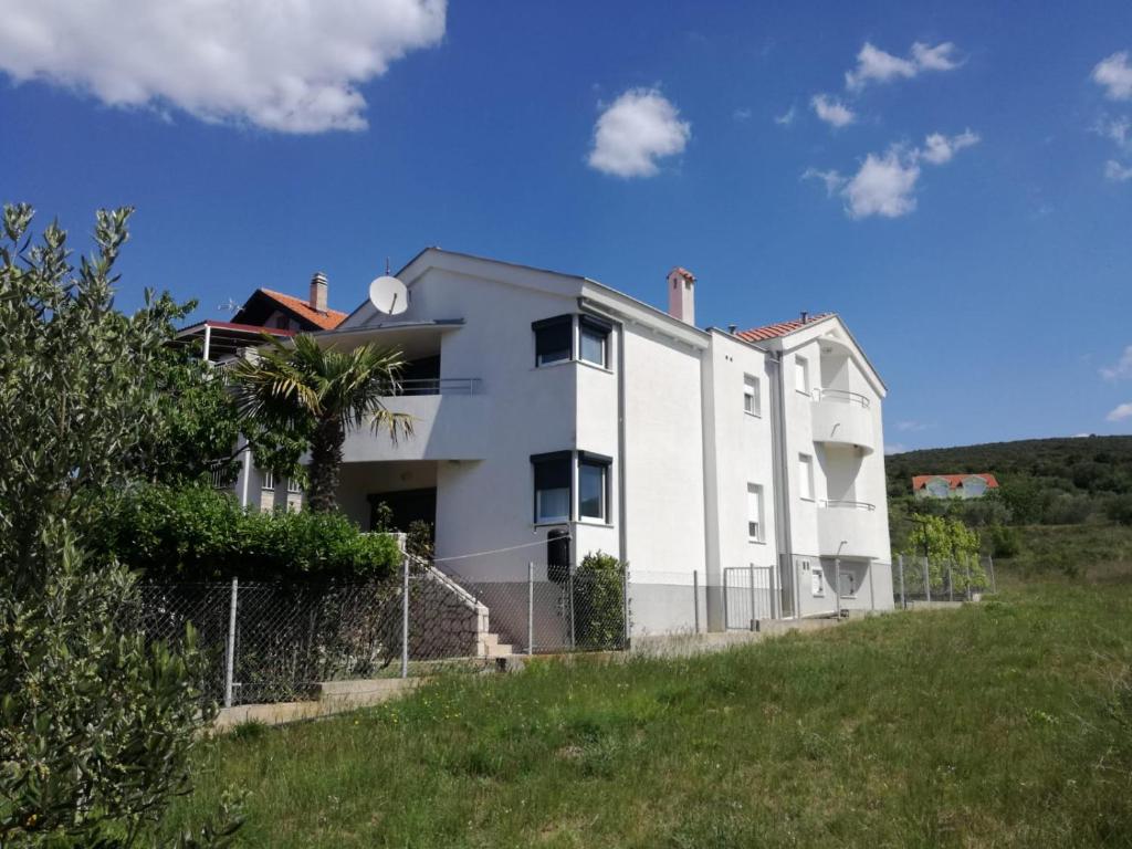 biały budynek na szczycie trawiastego wzgórza w obiekcie Apartments Maleo w mieście Sveti Petar