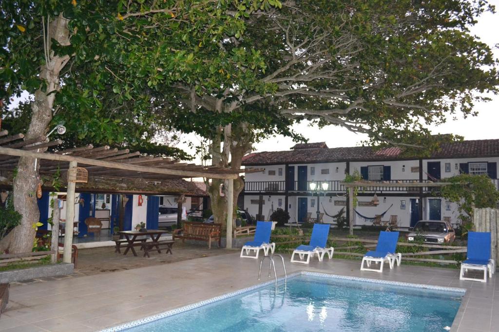 una piscina con sillas azules y blancas junto a una casa en Pousada Maria Farinha, en Búzios