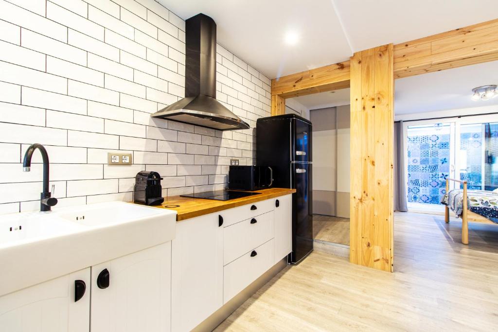 a kitchen with white cabinets and a black refrigerator at Chic y sofisticado Loft en la playa in Valencia