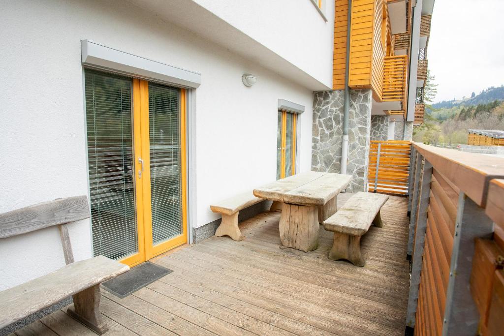 einen Balkon mit Bänken und einem Tisch auf einem Gebäude in der Unterkunft Apartments Plan Kranjska Gora in Kranjska Gora