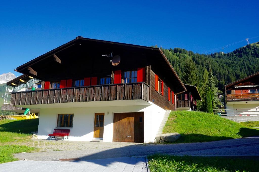 a building with a balcony with red doors at Ferienhaus Kuster in Sedrun