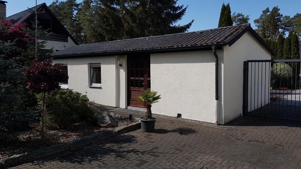 een klein wit huis met een poort en een potplant bij Ferienhaus am Mühlenweg in Winsen