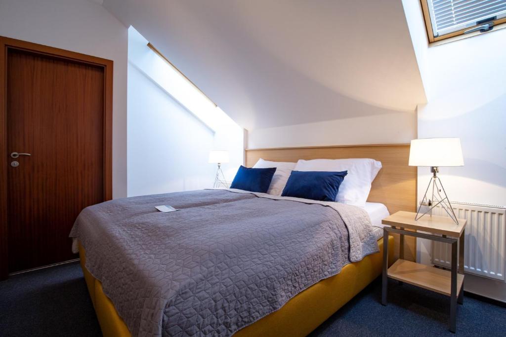 a bedroom with a large bed with blue pillows at Greensgate Hotel Dýšina in Horomyslice