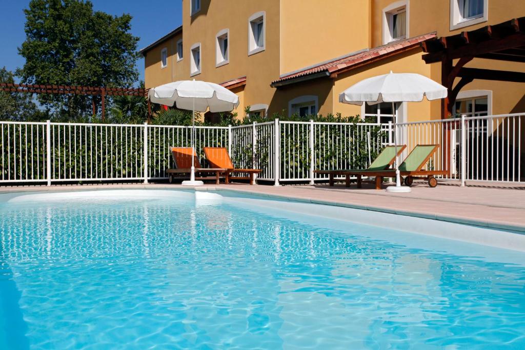 馬諾斯克的住宿－宜必思馬諾斯克卡達拉切酒店，一座带椅子和遮阳伞的游泳池位于一座建筑旁边