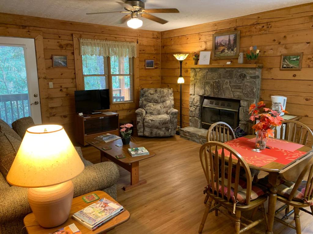 uma sala de estar com uma mesa e uma lareira em Misty Creek Log Cabins em Maggie Valley