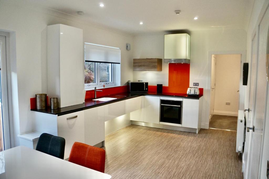 a kitchen with white cabinets and red accents at Leworin in Stirling