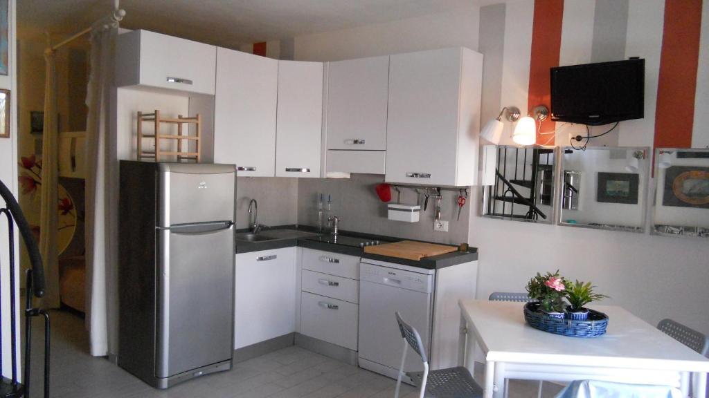 a kitchen with white cabinets and a stainless steel refrigerator at Nicola's Apartments in Marina di Campo