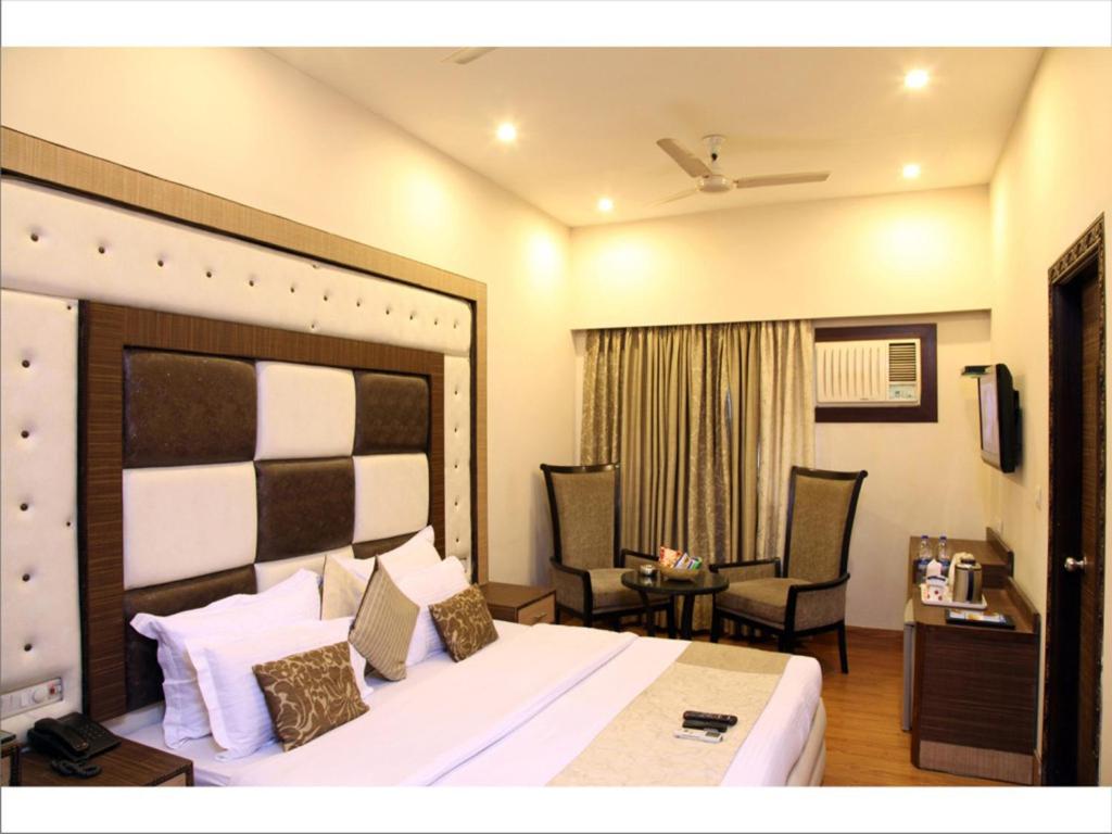 Habitación de hotel con 1 cama grande y 2 sillas en Rupam Hotel, en Nueva Delhi