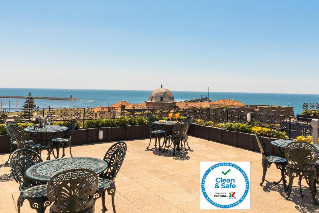 a patio with tables and chairs and a view of the ocean at Hotel Boa - Vista in Porto