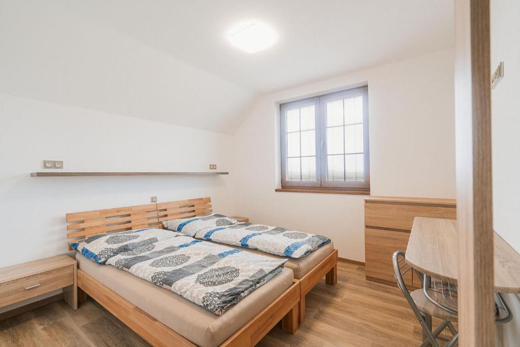 1 dormitorio con cama, escritorio y ventana en Penzion Dvojka, en Velké Bílovice