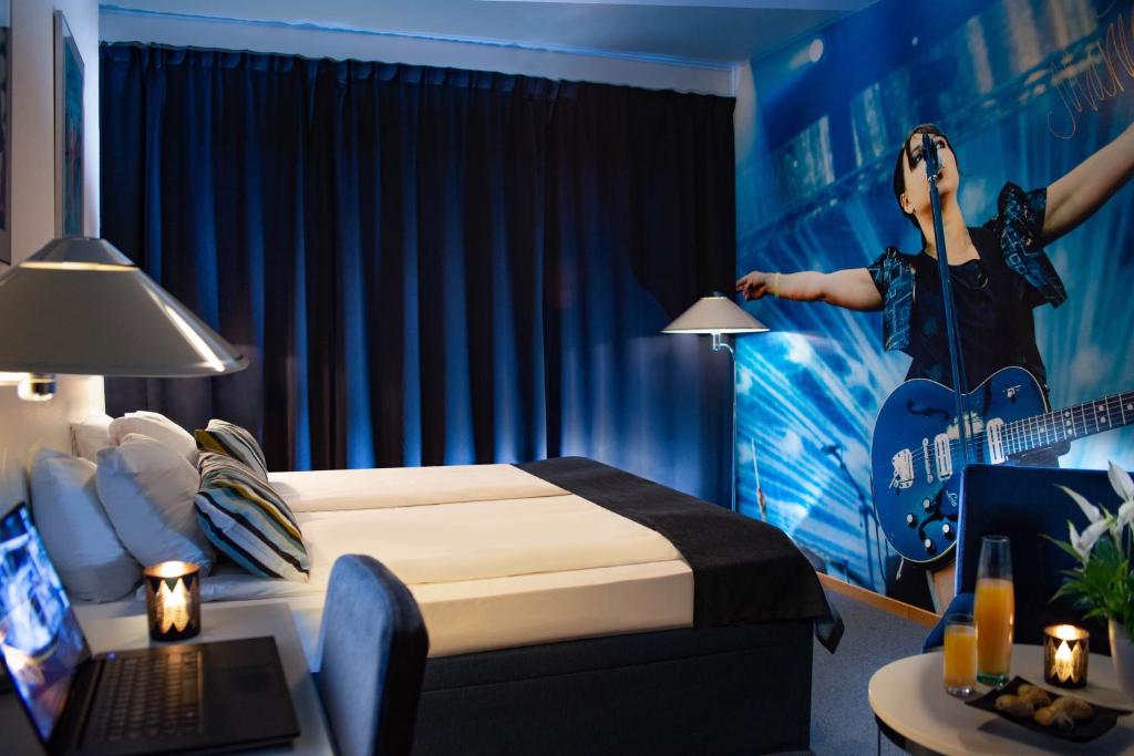 ein Hotelzimmer mit einem Bett und einem Wandbild einer Frau, die Gitarre spielt in der Unterkunft Hotell Hulingen in Hultsfred