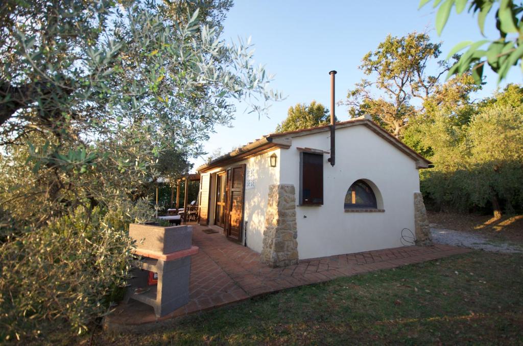 ein kleines weißes Cottage mit einem gemauerten Gehweg in der Unterkunft CASE&COLLINE Tramontina in Guardistallo