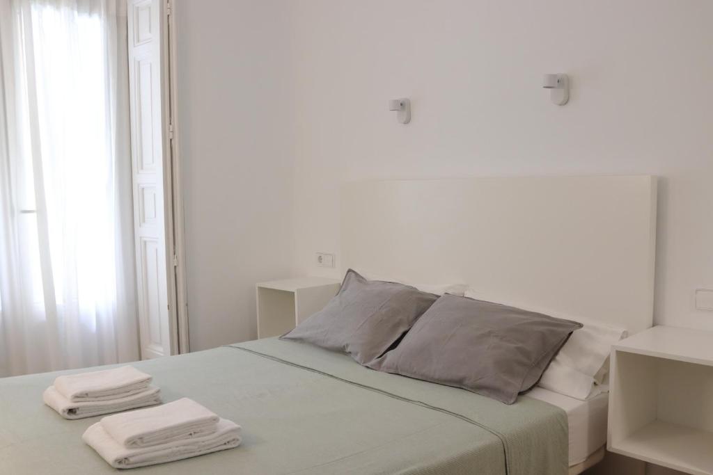 a white bedroom with a bed with two towels on it at Hostal La Zona in Madrid