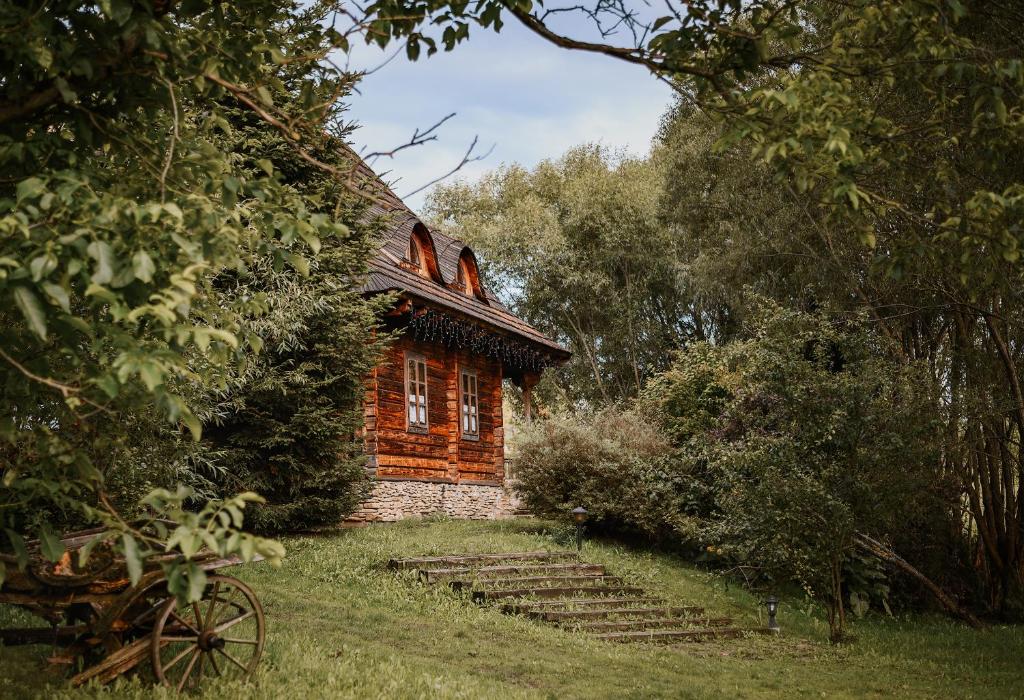 a log cabin in the middle of a yard with trees at Przystanek Ropienka Leśniczówka in Ropienka