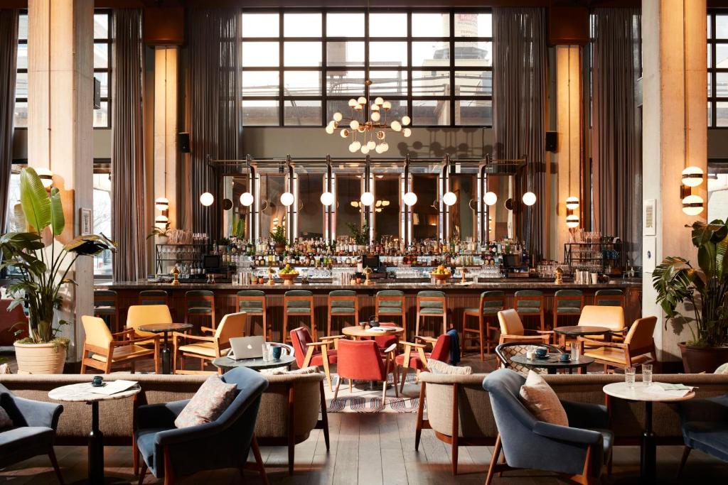un restaurante con un bar con mesas y sillas en The Hoxton, Chicago, en Chicago