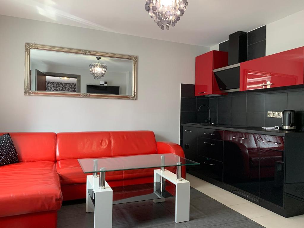 a living room with a red couch and a glass table at Migor Apartamenty in Łeba