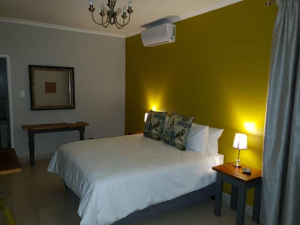 una camera con un letto bianco e una parete gialla di Poetry Guestrooms a Vryburg