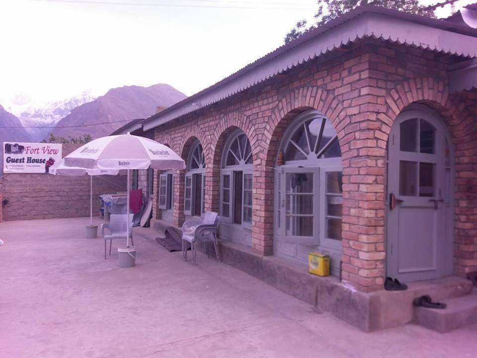 a brick building with an umbrella and tables and chairs at Fort View Guest House in Baltit