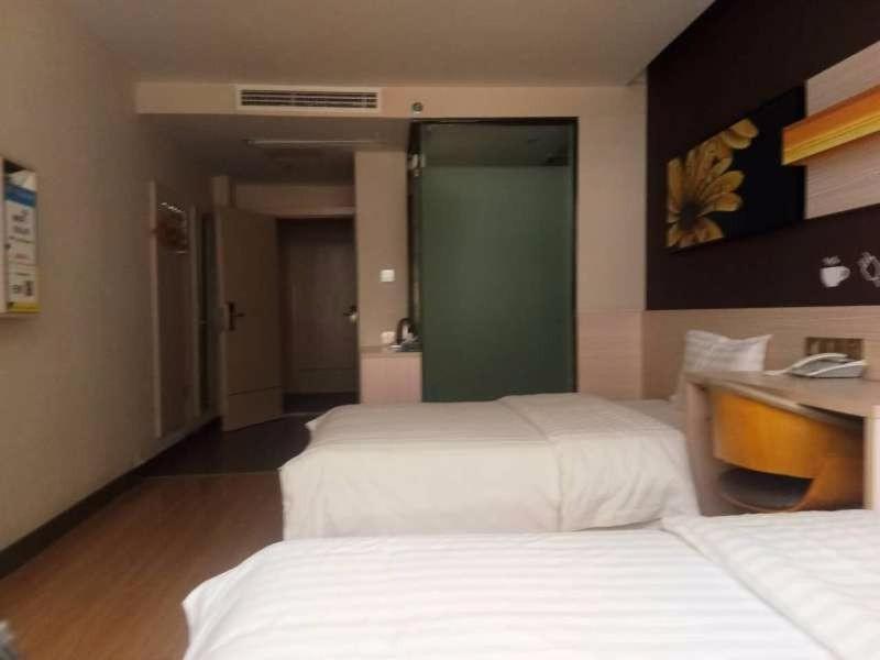 een hotelkamer met 2 bedden en een bureau bij 7Days Inn Yueyang Pingjiang Tianyue Road Pedestrian Street in Pingkiang-hsien
