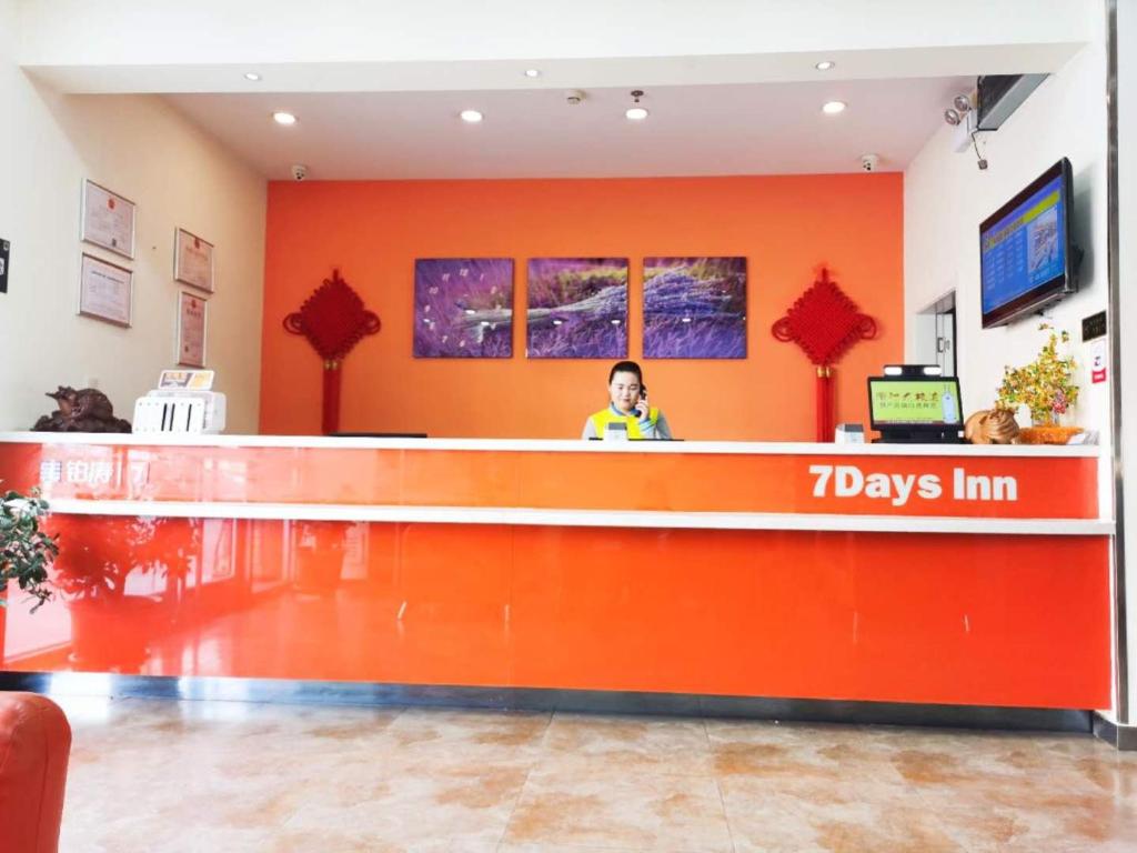 a woman standing at the counter of a days inn at 7Days Inn Jinchang Culture Street in Jinchang