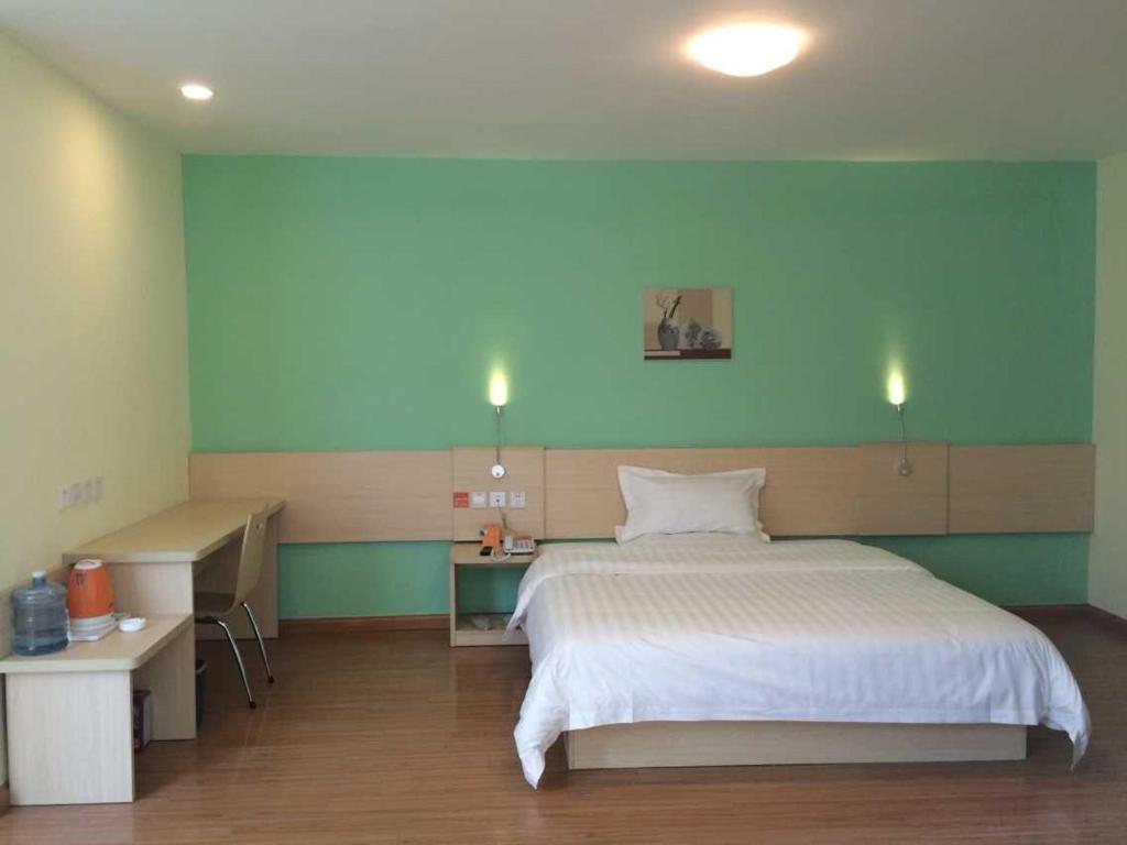 um quarto com uma grande cama branca e uma secretária em 7Days Inn Guangrao Bus Terminal em Dongying