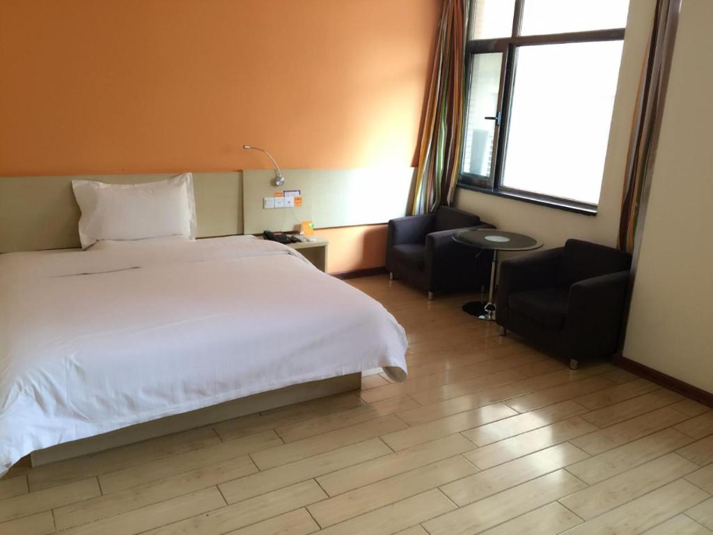 a bedroom with a large white bed and two chairs at 7Days Inn Lintao city Gold street in Taoyang