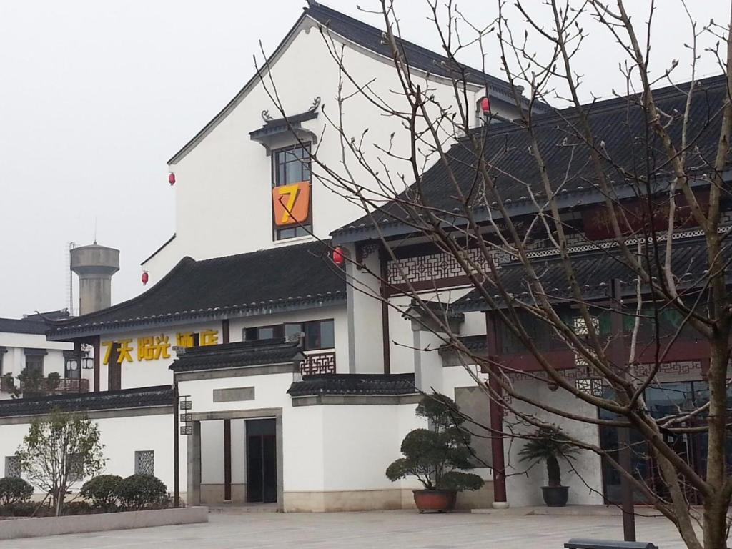 een groot wit gebouw met een vlag erop bij 7Days Inn Suzhou Luzhi Ancient town in Dashi