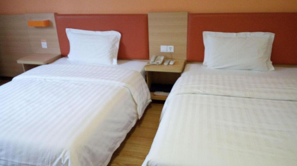 2 łóżka w pokoju hotelowym z białą pościelą w obiekcie 7Days Inn Yongzhou Lengshuitan Shun De mol of BBK Plaza w Yongzhou