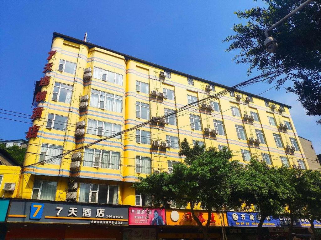 um grande edifício amarelo com janelas numa rua em 7Days Inn ChengDu RenShou Shuyuan Road Haochi Street em Meishan