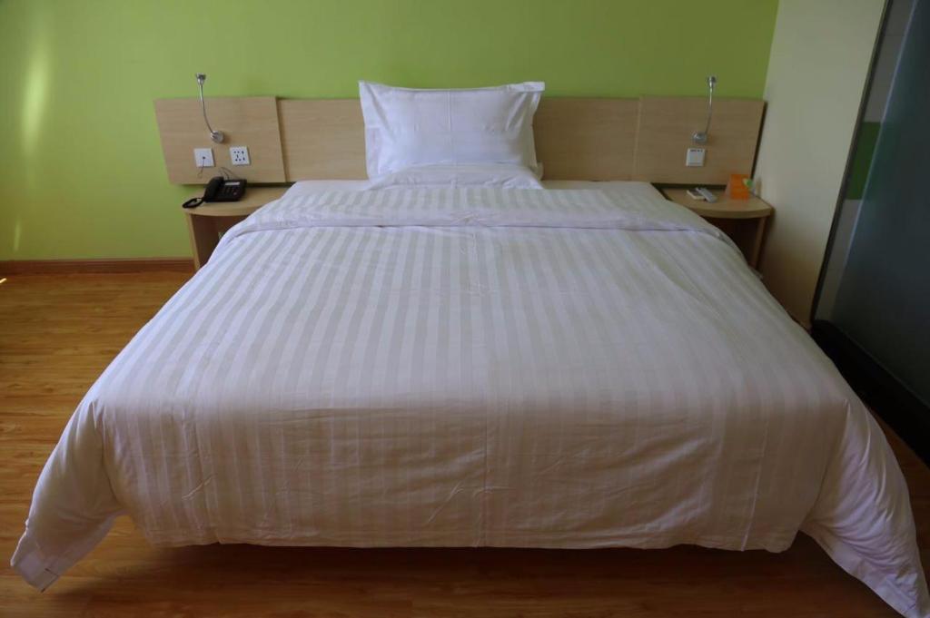 uma grande cama branca num quarto com duas mesas em 7Days Inn Hami Baofeng Market em Hami