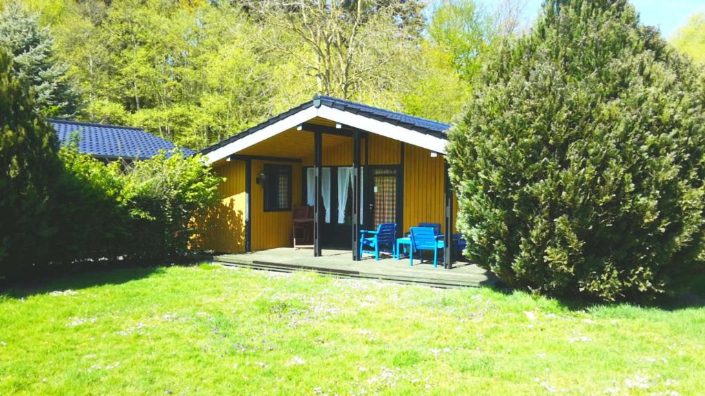 a small yellow house with blue chairs in a yard at Retro Chalet Nr 3 in Kellenhusen