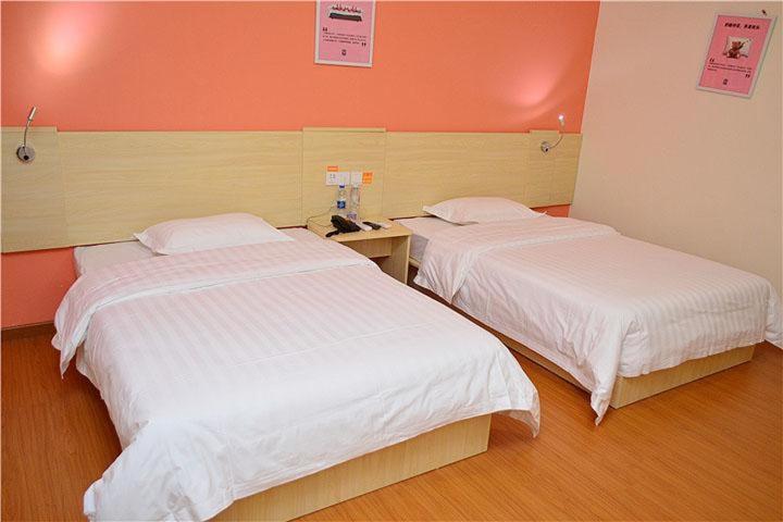 2 Betten in einem Zimmer mit orangefarbenen Wänden in der Unterkunft 7Days Inn Shaoguan Lechang Darunfa in Shaoguan