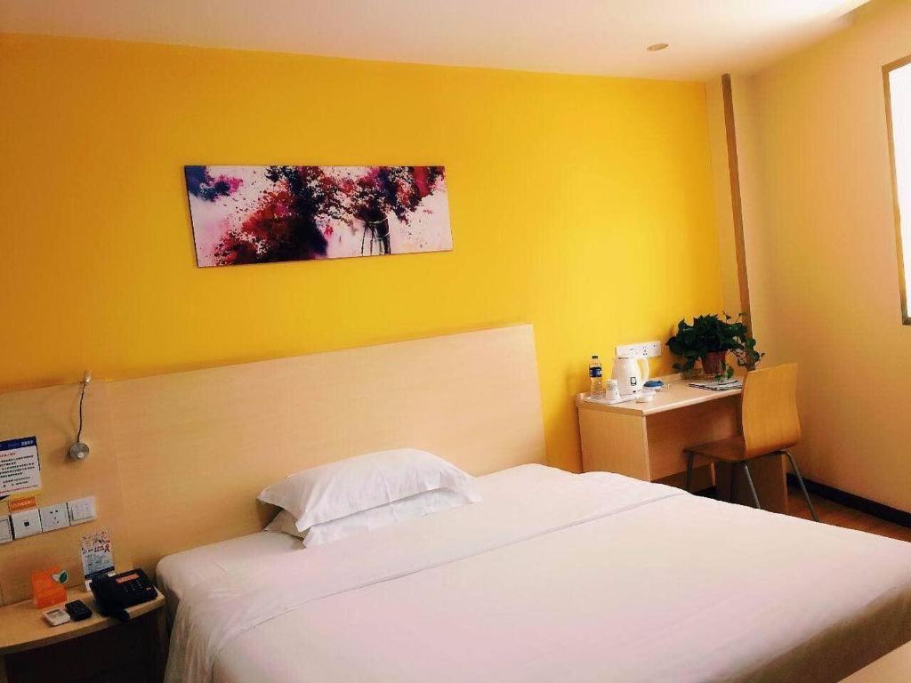 een slaapkamer met een wit bed en een gele muur bij 7Days Inn Hanzhong Tianhan Avenue South Station in Hanzhong