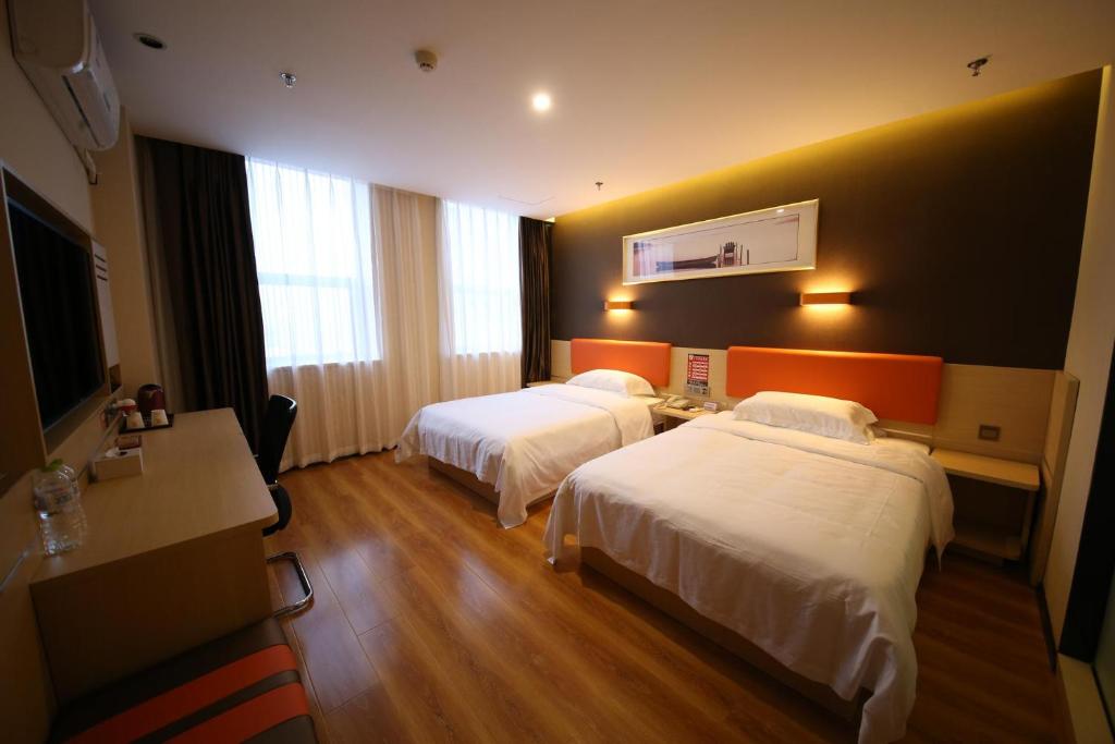 a hotel room with two beds and a television at 7 Days Premium Dezhou Pingyuan Xinhua Road in Dezhou