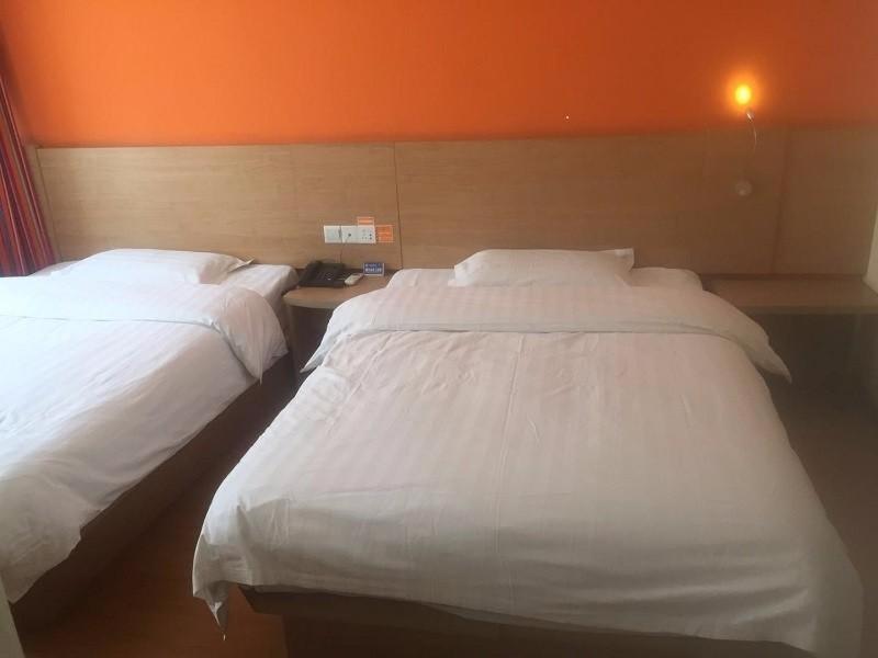 2 weiße Betten in einem Zimmer mit orangefarbener Wand in der Unterkunft 7Days Inn Jixian County Road in Shuangyashan