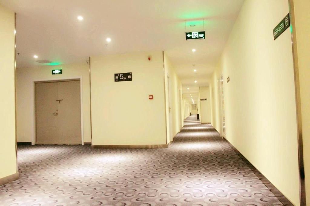 un corridoio vuoto con porte bianche e pavimenti piastrellati di 7Days Inn Weinan Jiefang Road railway station a Weinan