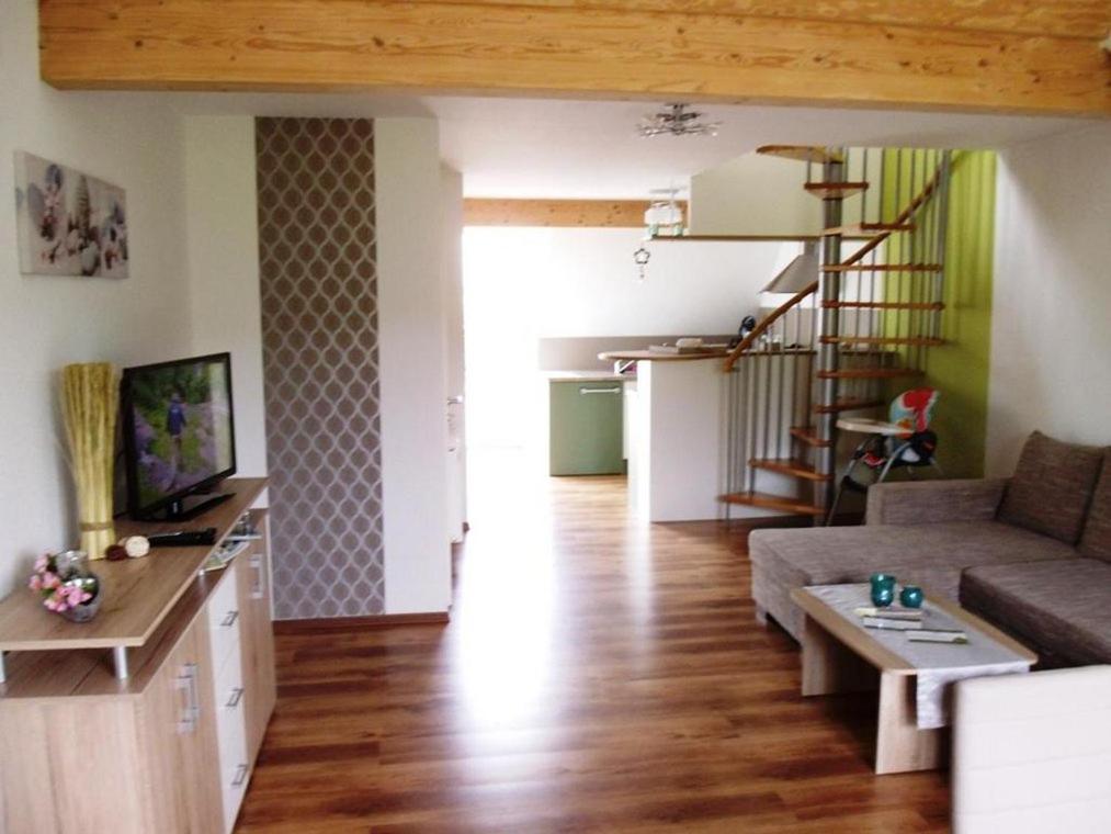 ein Wohnzimmer mit einem Sofa, einem Tisch und einer Treppe in der Unterkunft Landhaus Nobel-Hobel in Kommen