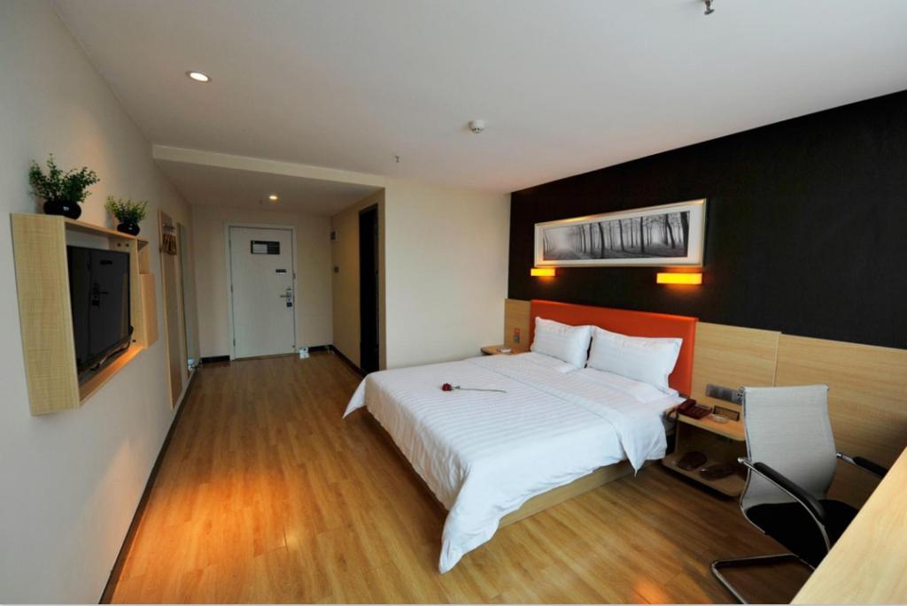 a bedroom with a large white bed and a flat screen tv at 7Days Premium Chongqing Fengjie Kuizhou Avenue in Fengjie