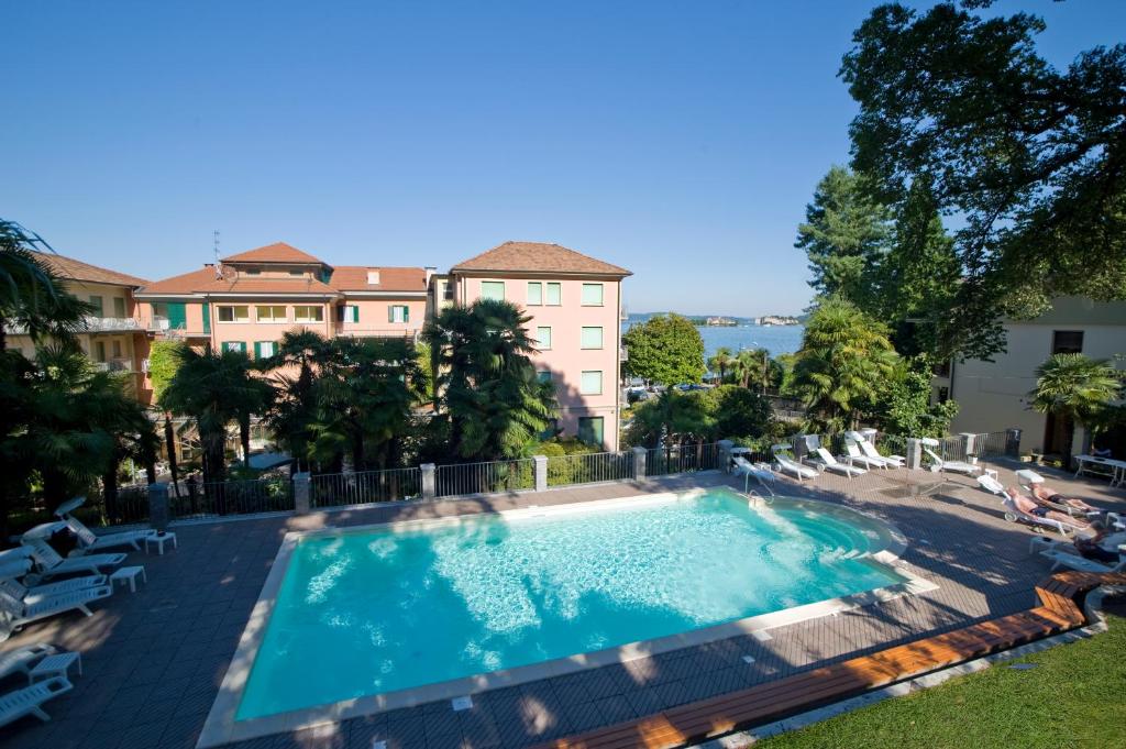 a large swimming pool with chairs and a building at Hotel Beau Rivage in Baveno
