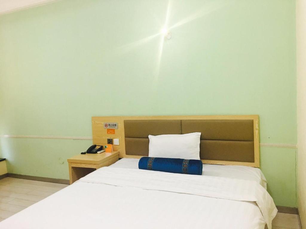 a bedroom with a white bed with a blue pillow at 7Days Inn Harbin Railway Station Zhanqian Square in Harbin