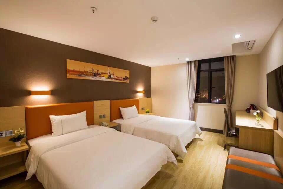 een hotelkamer met 2 bedden en een televisie bij 7Days Premium Zhuzhou Yangtze River Road Central Hospital in Zhuzhou