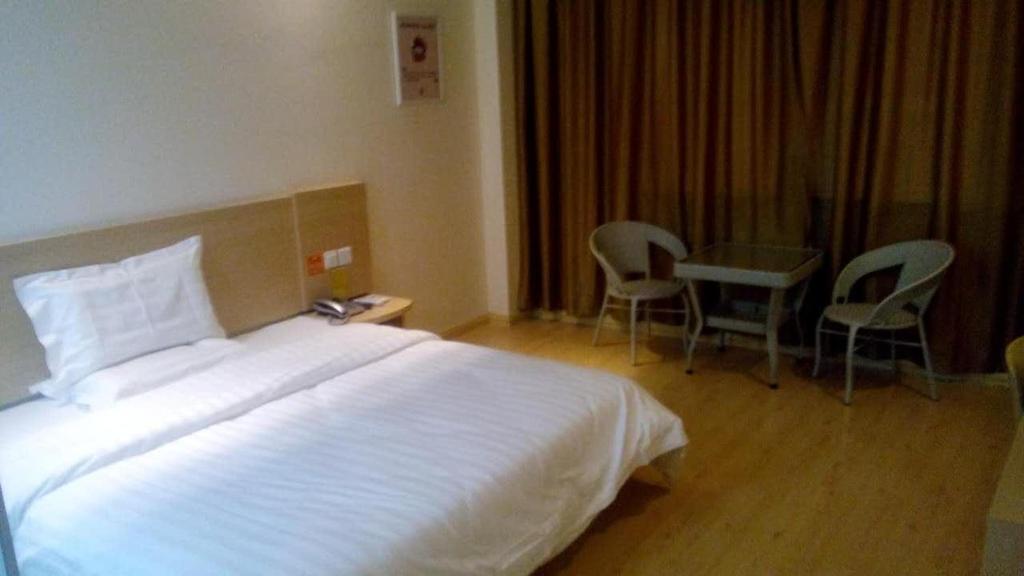 a hotel room with a bed and a table and chairs at 7Days Inn Huaian vehicle administration in Huai'an