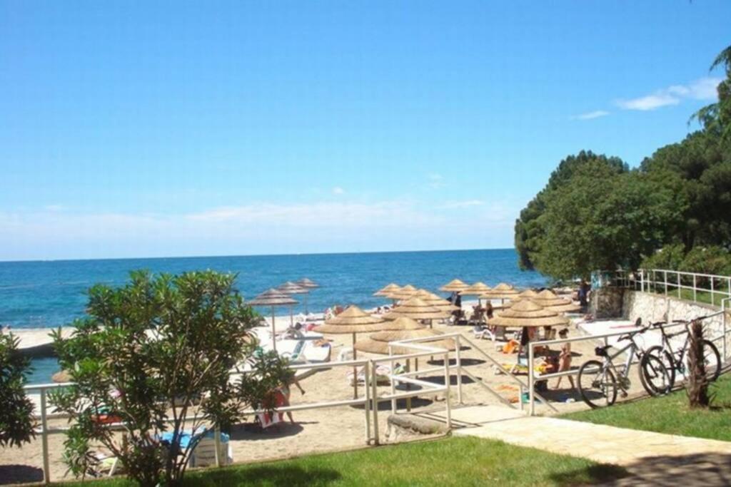 a beach with tables and umbrellas and the ocean at Apartment Nebo in Poreč