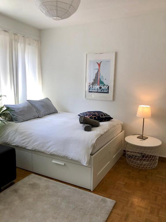 1 dormitorio con 1 cama blanca con lámpara y ventana en The Paquis Oasis in Central Geneva, en Ginebra