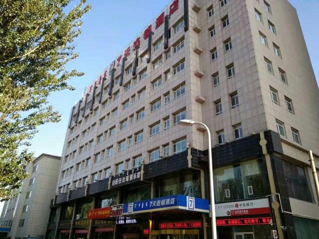 un grand bâtiment au coin d'une rue dans l'établissement 7Days Inn Dongsheng Railway Station, à Zhaoyoufang