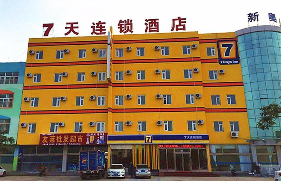 un edificio amarillo con coches estacionados frente a él en 7Days Inn Rizhao Development Zone, en Rizhao