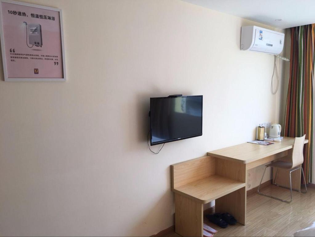 een kamer met een bureau en een tv aan de muur bij 7Days Inn Yiyang victory road in Shangrao