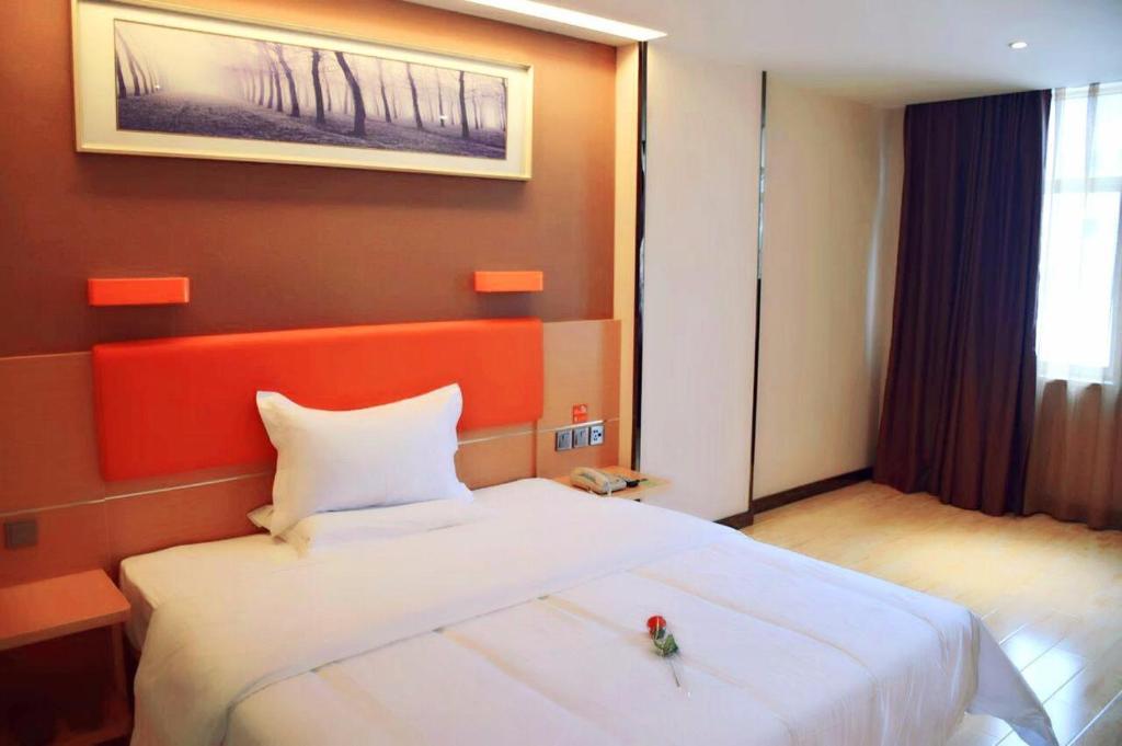 um quarto com uma cama branca e uma cabeceira vermelha em 7Days Premium Changsha Sanyi Avenue Guofangkeda em Changsha
